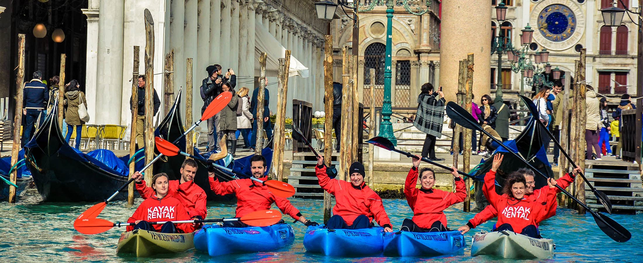 A Venice By Water tour group with paddles raised in front of St Mark's Square